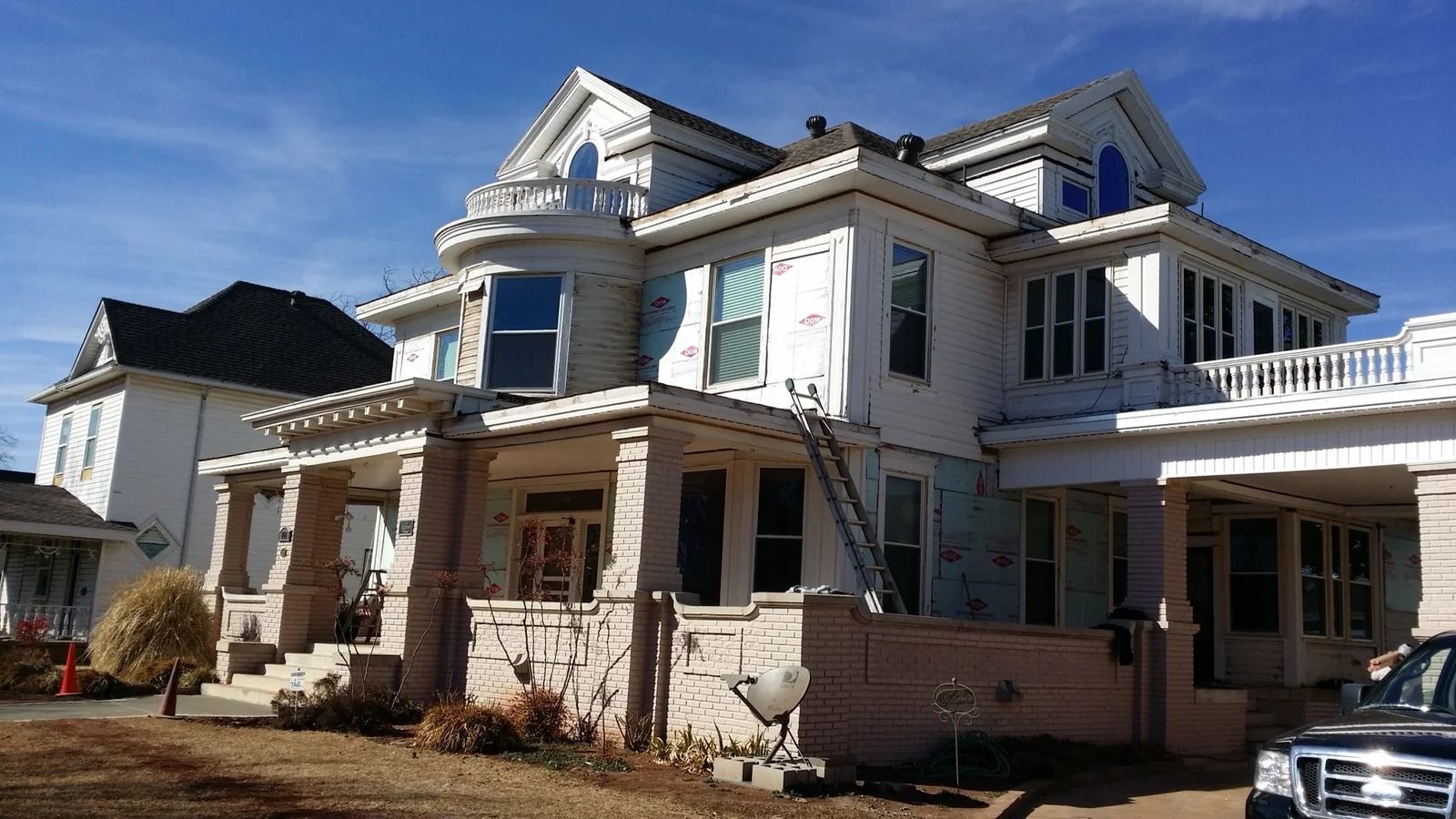 Two-story white home before window and siding replacement