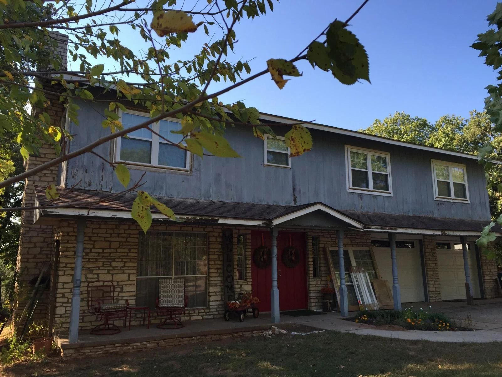 Two-story home with faded siding before replacement